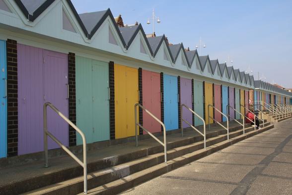 A line of beach huts with pastel coloured doors.