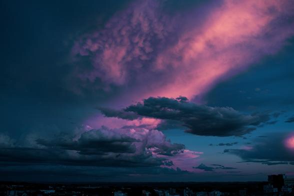 A stock photo by Mateus Campos Felipe, via Unsplash.com, of a pink, blue, and dark grey cloudy night sky.