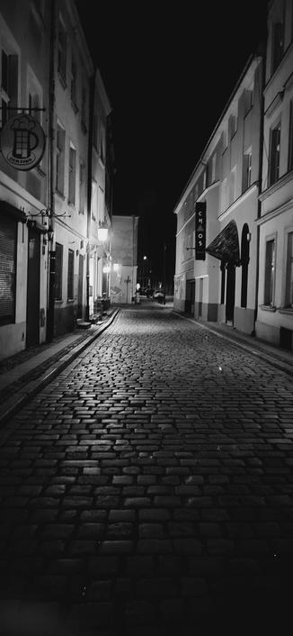 Black and white photo of cobbled street at night in Poznań,  Poland