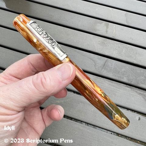 Side view of Idyll fountain pen showing how the silver panel roll stop curves to fit the cap. Held in maker’s hand.