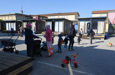 un ensemble de petites maisons sur roues.
Devant, des femmes, des jeunes enfants, des poussettes,  un tricycle rouge