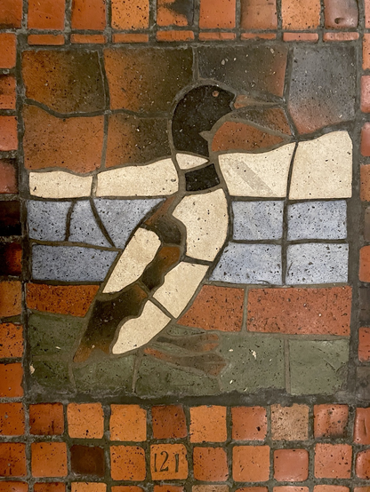Multicolored tile mosaic depicting a loon standing in side profile, on red tile mosaic floor, numbered “121.”