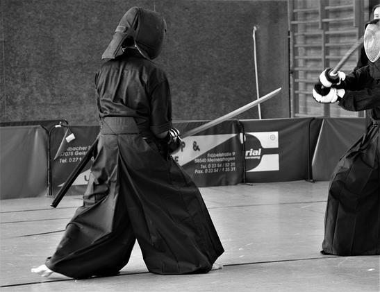 Two persons with armour and wooden swords fighting. The defender is in the middle base position - chudan-kamae.