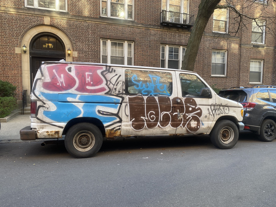 throwups on the side of a white van including DEST in pink and blue and TOCER in brown
