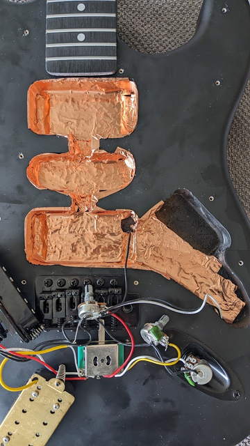 Electric guitar that has been disassembled and copper shielding tape applied to the inside