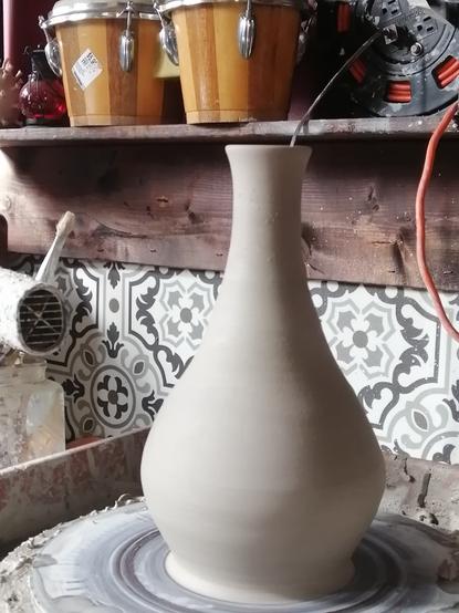 A tapered vase on the pottery wheel.