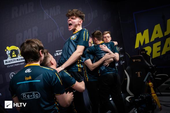 Polski zawodnik GamerLegion, z triumfalnym okrzykiem podnoszony przez kolegę z zespołu, w tle kolejnych trzech zawodników obejmujących się
