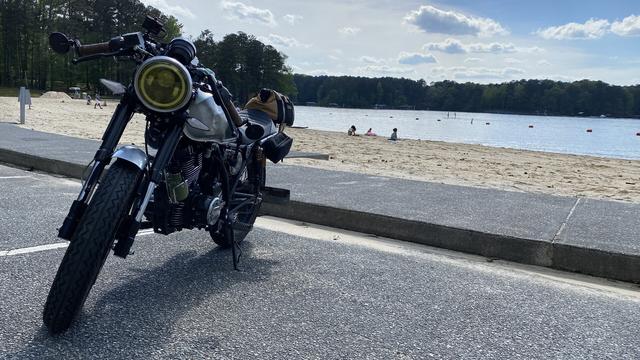 A cafe racer motorcycle parked at a lakeside beach