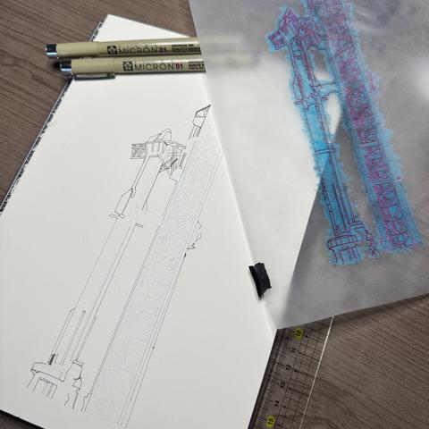 An ink drawing of the Starship/Falcon Super Heavy booster stack and launch tower with used tracing paper, ruler and ink pens lie on a grey desk, partially inked.
