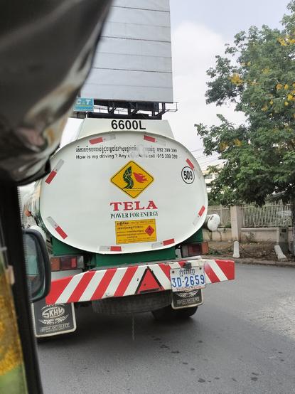 A warning -it's-flammable sign on the back of a tanker truck in Cambodia. It depicts three of the seven heads of a naga. A naga is a mythical snake based on a cobra. It is green and breathing red flames.