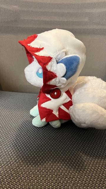 An Alolan Vulpix plushie, wearing a hand-crafted White Mage cloak. Side view.
