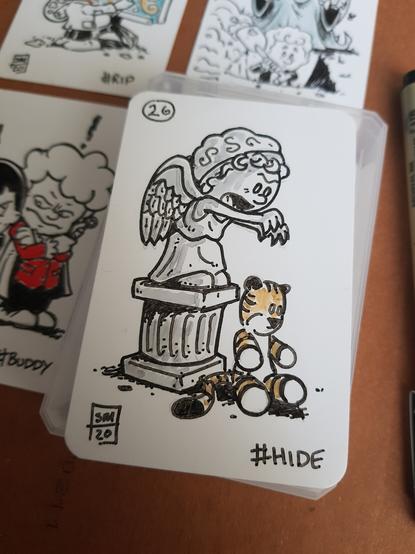 A photo of an ink doodle drawn on a blank playing card. In a Calvin and Hobbes cartoon style. We see a stuffed toy tiger that looked like Hobbes sitting in front of and facing away from a stone pedestal with a rather angry looking weeping Angel getting ready to grab the toy. The weeping Angel looks like Calvin.
