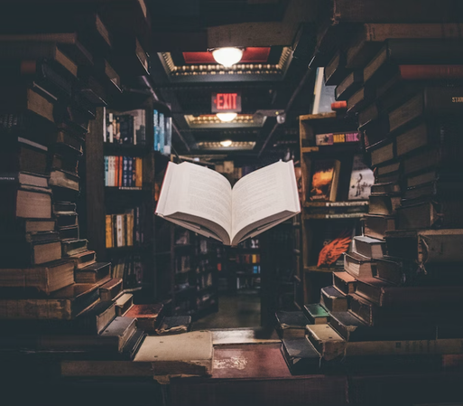 A book hovers magically in a ring of stacked books, lit dramatically.