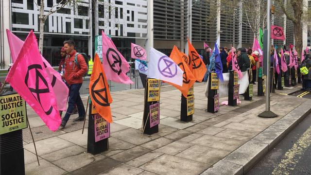 XR flags on bollards outside the Home Office, and placards saying "Climate justice is social justice"