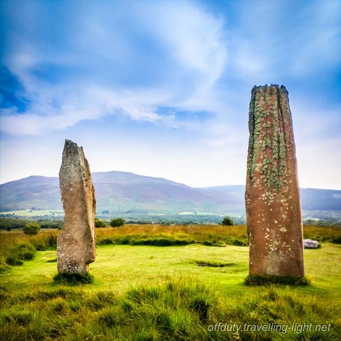 Two standing stones in a circle of grass on moorland.