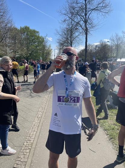 Foto von mir direkt nach dem Zieleinlauf mit Rennsandalen in der einen Hand und Bier in der anderen.