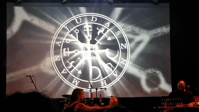 Concert of Judasz & Nahimana. Picture of the scene. Musicians in front and the band logo in the background.