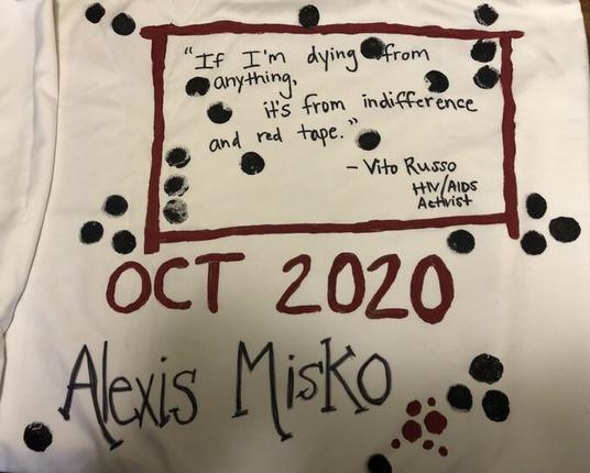 Name (Alexis Misko) and date (Oct. 2020) are at the bottom in large letters. Above that is a quote, written in smaller letters and inside a red rectangle: "If I'm dying from anything, it's from indifference and red tape." - Vito Russo, HIV/AIDS activist. The design also includes black dots scattered across the pillowcase.