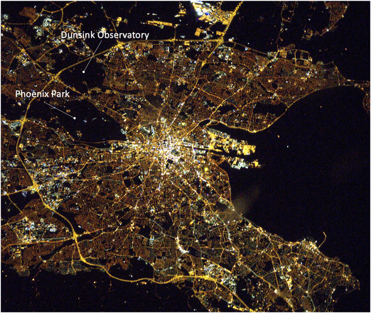 Satellite image of Dublin at night, showing very lit up areas in the city centre but dark areas where there aren't so many lights at Phoenix Park and Dunsink Observatory