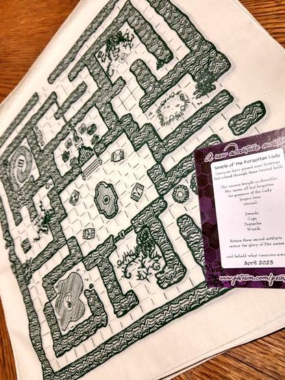 A cloth natural cotton TTRPG map printed in forest green, with a little optional lore card.