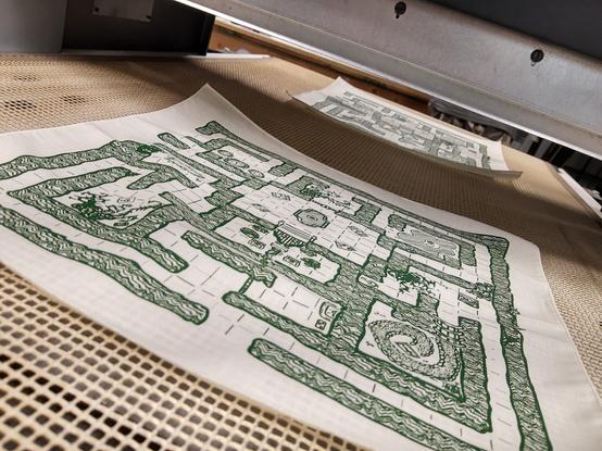 Two printed cloth maps coming through the conveyor dryer, which cures the ink to the fabric