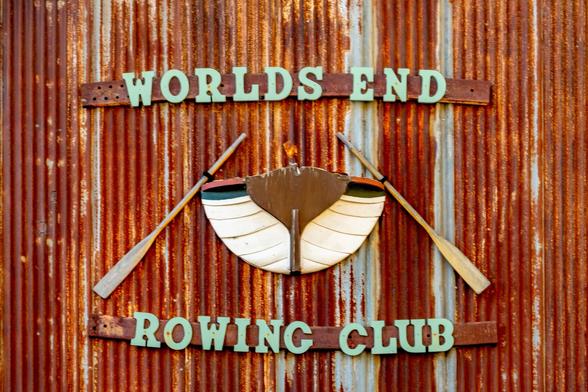 Worlds End

Captured in Noyo Harbor, Ft. Bragg, California. 
This image is of a rusted, corrugated steel, sliding door that opens to an old boat barn that belongs to the Worlds End Rowing Club.
The center of the image shows a wooden row boat with two oars hanging off of the side. The view of the boat is straight on.
Above the boat are the words, "Worlds End" and below the boat are the words, "Rowing Club:.