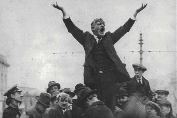 Photograph of James Larkin speaking to a crowd with his arms held up.
