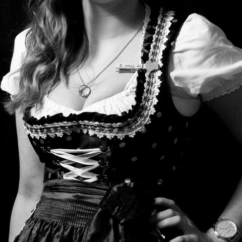 Quadratische Schwarz-Weiss-Fotografie des Körpers einer jungen Frau im Dirndl.