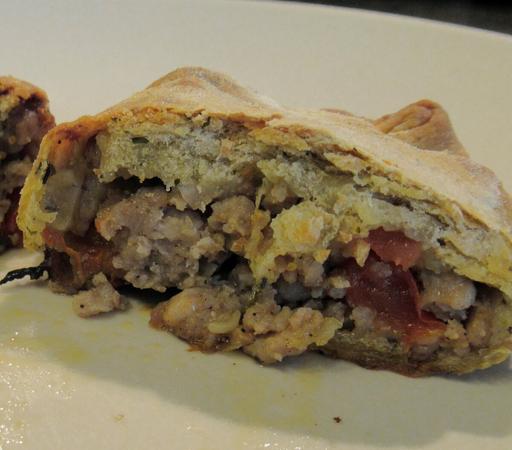 Der "Pizzakeks" aufgeschnitten, zu erkennen ist der kross gebackene Teig als Mantel, darin eine Füllung aus Hackfleisch, Paprika, Käse und Gewürzen.