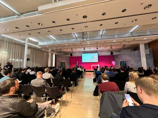 Ein voller Konferenz-Raum im Telekom Campus mit ca. 150 Teilnehmenden.