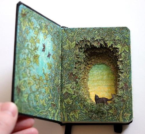 A book transformed by glue and carving to display a three-dimensional cat in a forest, surrounded by vines.