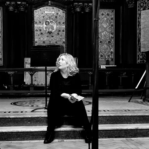 Black and White image of woman sitting on steps in a church.