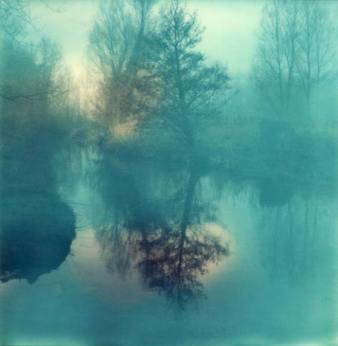 A predominantly blue colour Polaroid taken on Impossible Project film. It shows trees, the river and a reflection taken on a misty day