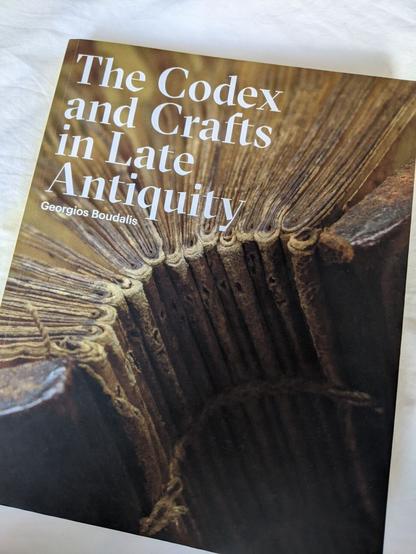 Book cover showing multiple bifolio sections sewn with a link stitch between wooden boards.