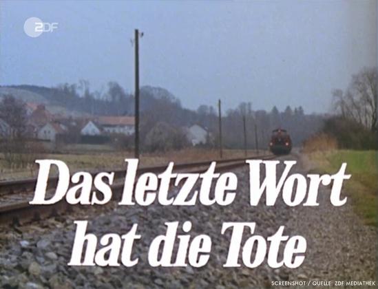 Blick über das Lokalbahngleis auf Haag an der Amper. Im Hintergrund nähert sich ein Güterzug, im Vordergrund ist der Folgen-Titel "Das letzte Wort hat die Tote" eingeblendet.