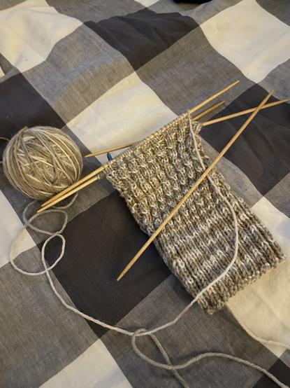 Beige and tan sock yarn with a half knitted wool sock
