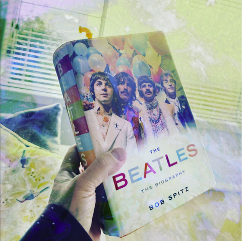 A far-out picture of a hand holding a copy of THE BEATLES: THE BIOGRAPHY by Bob Spitz, in hardback.
