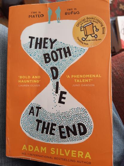 Book cover: orange background. A white hourglass shape with turquoise and grey grains of sand falling through. The title words, in black, also falling through. Two silhouetted figures stand on top. One marked "This is Mateo", the other "This is Rufus". Author name at the bottom in yellow.