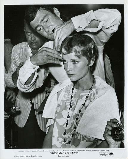 A promotional photo for Rosemary's Baby. Sassoon cuts Farrow's hair. She looks intensely in a mirror (I assume). Around them, several pressmen with photo cameras are visible.