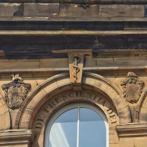 A carving on a sandstone building shows an upright rod with a snake wrapped around it.