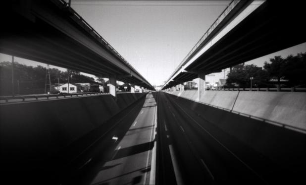 On a small bridge looking down the upper and lower decks of Interstate 35.
There were several cars driving by during this shot, but the exposure was long enough that the road appears empty.