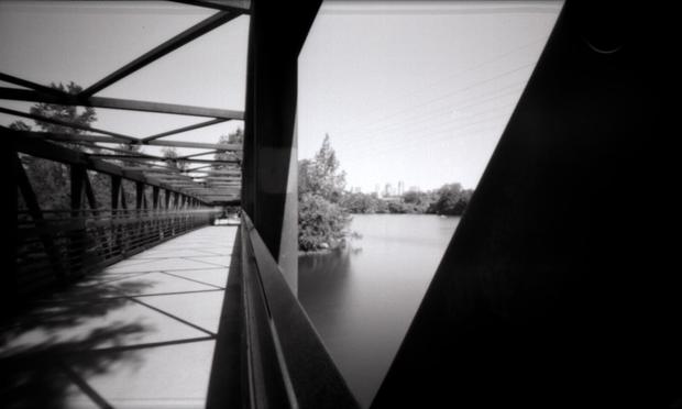 Shot from the rail of a pedestrian bridge, looking over part of Town Lake with downtown Austin, in the distance.
You can make out the streak of a cyclist that went by as this photo was taken.