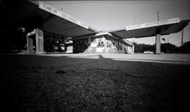 An old service station covered in tags and posters. Shot from the ground.