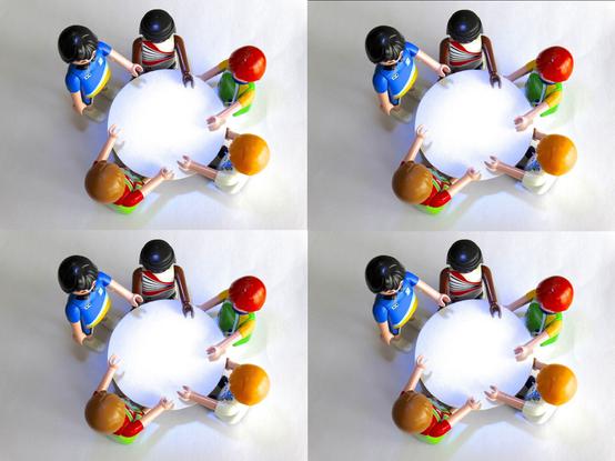Vier runde Tische mit Playmobilfiguren, die um die Tische herum stehen.
