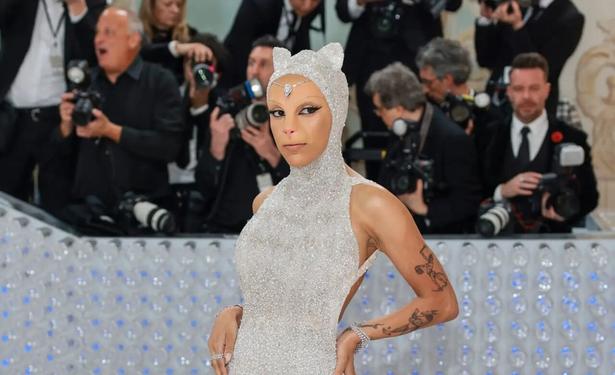 the singer Doja Cat with a cat nose and ears on her spangly silver jumpsuit