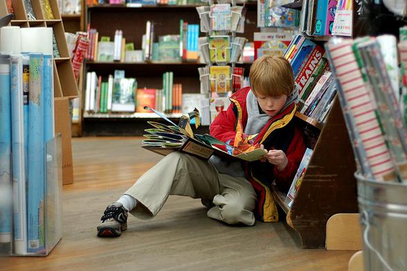 Ein Kind liest in der "Brookline Booksmith", einer unabhängigen Buchhandlung in Boston, Massachusetts. - Unbekannter Autor, CC BY-SA
