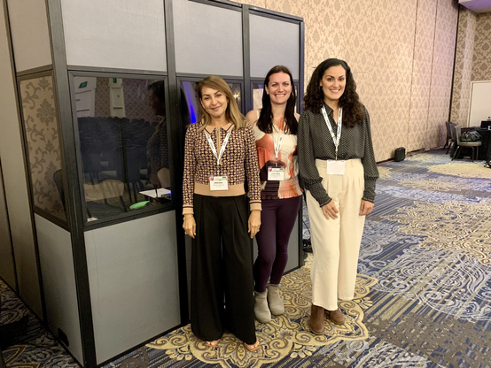 Three interpreters standing beside an interpretation booth.