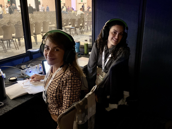 Two interpreters inside an interpretation booth.