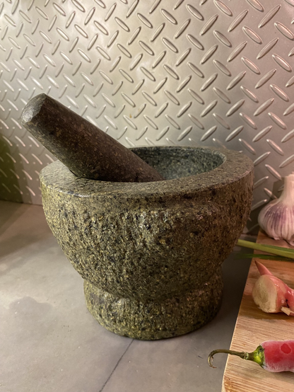 A granite mortar and pestle sitting on a kitchen bench