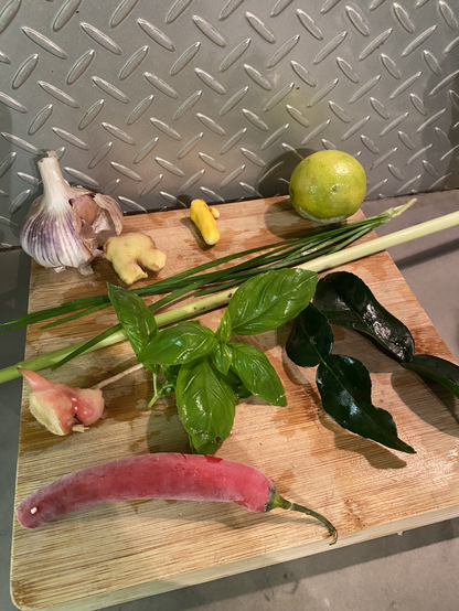 Freshly picked basil, ginger, galangal, tumeric, garlic chives, kaffir lime leaves, lemon grass, a chilli, some garlic and a lime - all ready for chopping on the bamboo cutting board and ground up to create an amazing chilli paste!